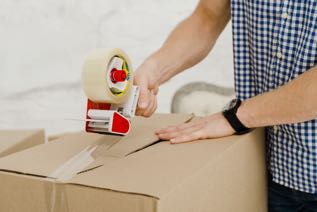 This image shows someone tapeing up a box for moving.