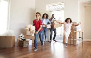 Excited Family Carrying Boxes Into New Home On Moving Day
